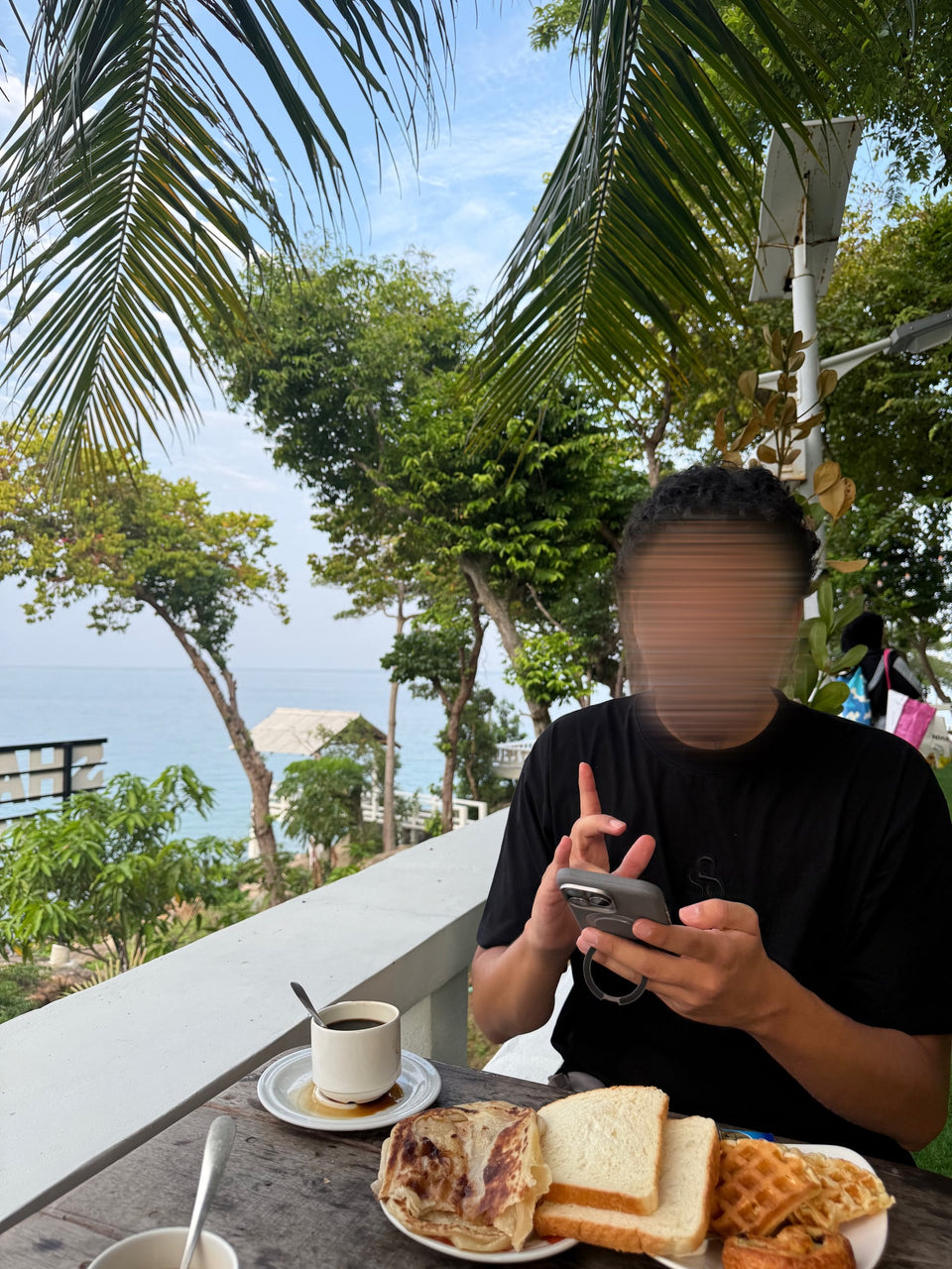 Un petit déjeuner en terrasse, avec un café et la mer en arrière-plan.